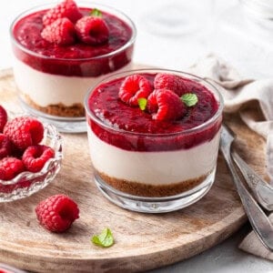 No Bake Vegan Cheesecake Jars garnished with raspberries, served on a wooden tray