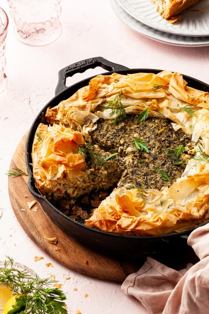 Side angle of a cast iron pan filled with a phyllo crusted spinach pie.