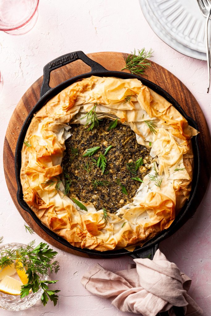A baked skillet spanakopita garnished with fresh dill.