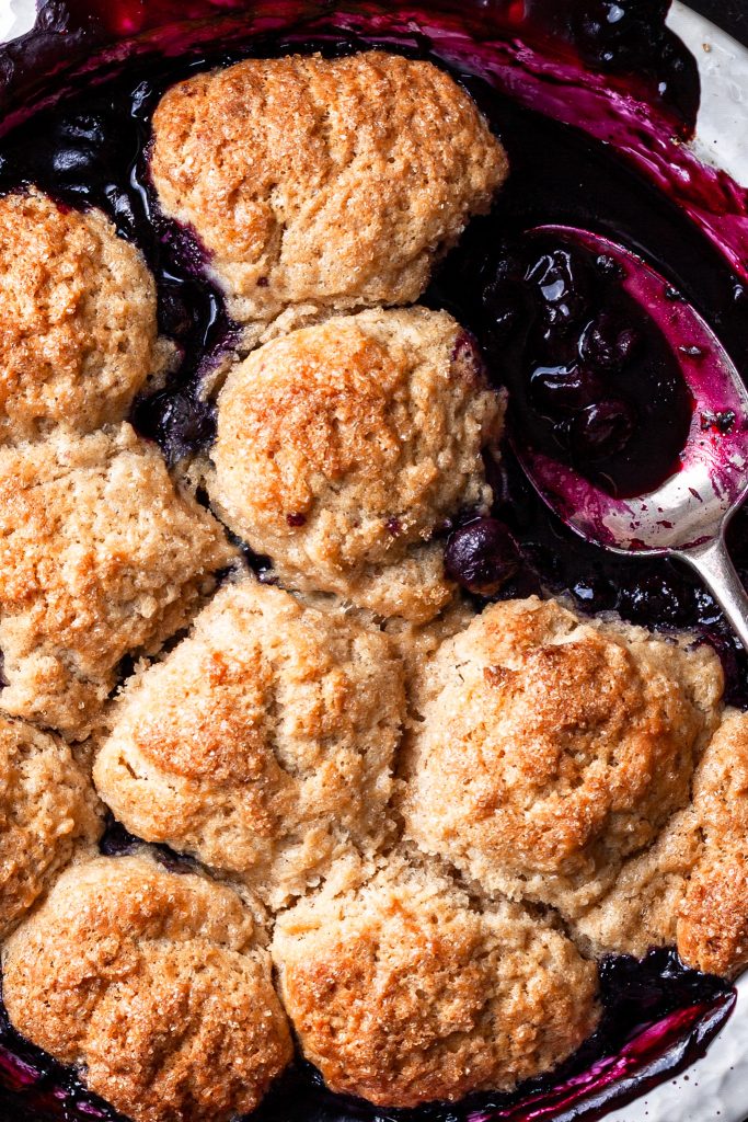 Close up of a blueberry cobbler, highlighting the tender golden drop biscuits. 