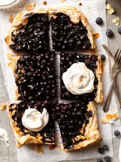 Berry tart into 6 large pieces, 2 of which are dolloped with whipped cream.